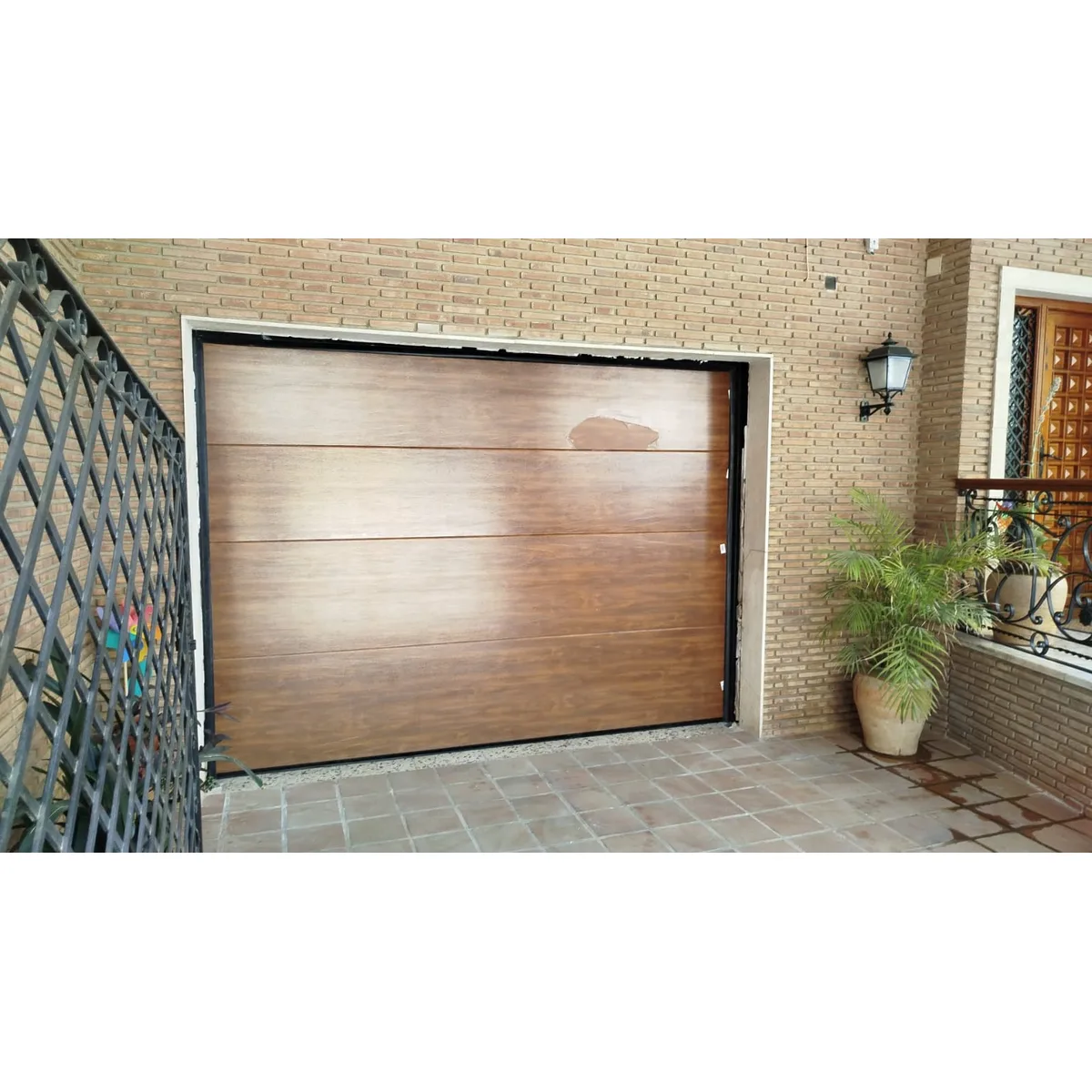 Puerta seccional de garaje con acabado madera instalada por Portaflex